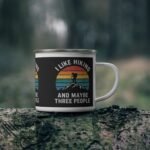 White enamel hiking mug with retro sunset and funny “I Like Hiking and Maybe Three People” quote design